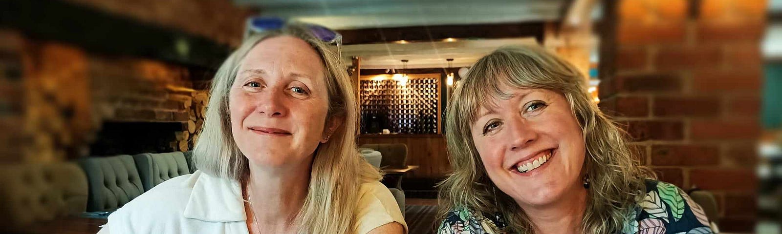 Two women are smiling and sitting at a table in a pub restaurant