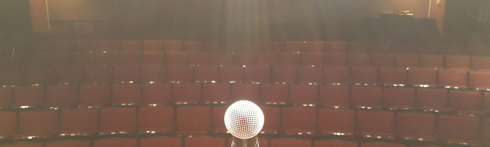 View from stage behind microphone looking into an empty theater.