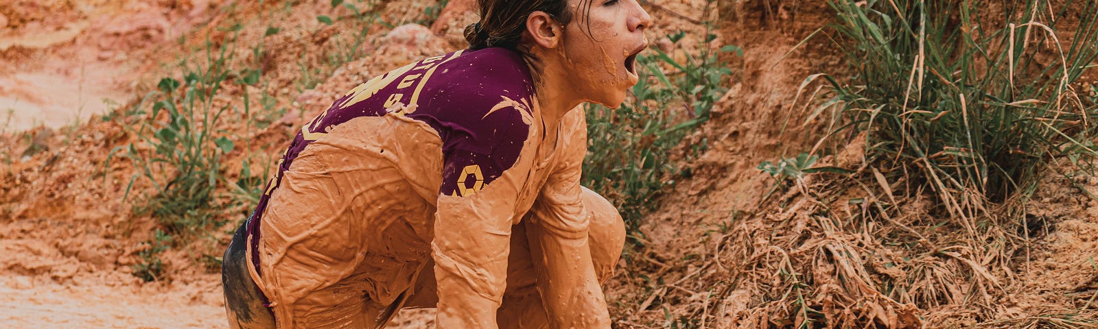 Woman crawling through the orange-brown mud.