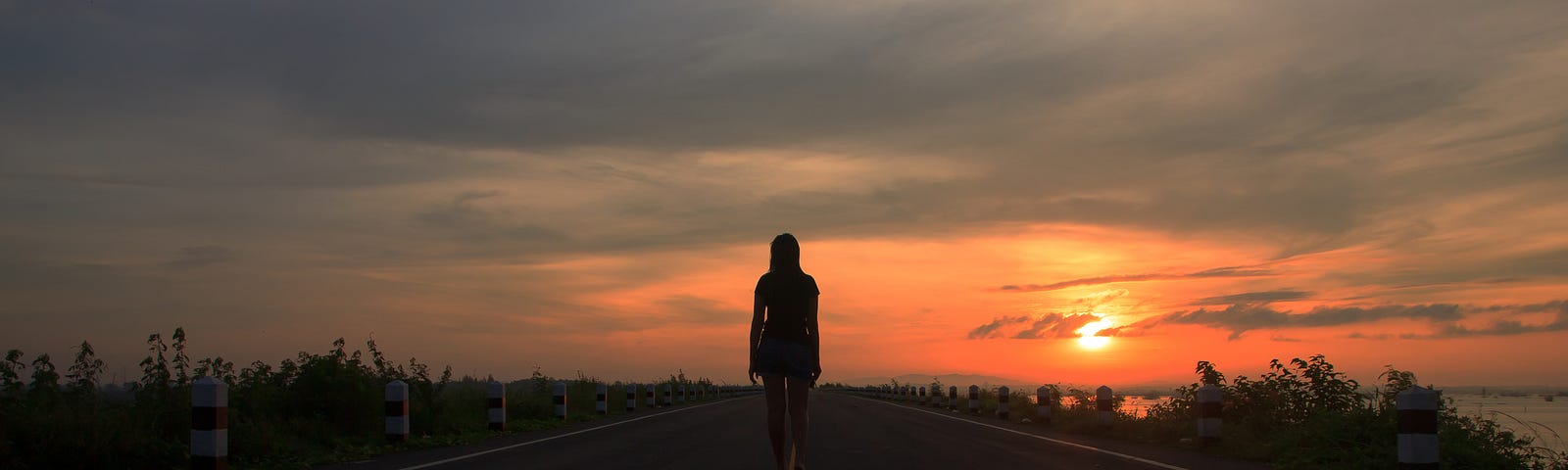 Girl walking alone at night on a deserted highway.