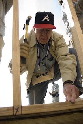 former President Jimmy Carter, volunteering, swings a hammer to build homes for Habitat for Humanity
