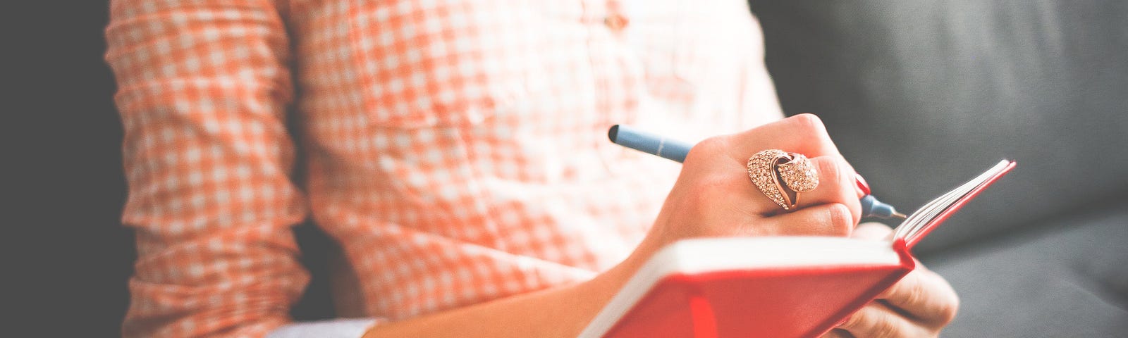 A woman writing in a red notebook.