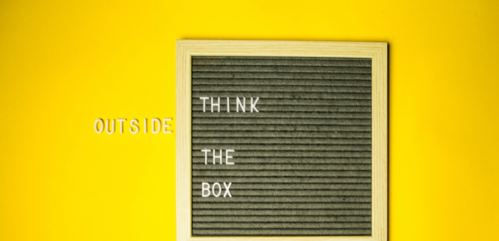 Yellow background with black box that states Think Outside The Box.