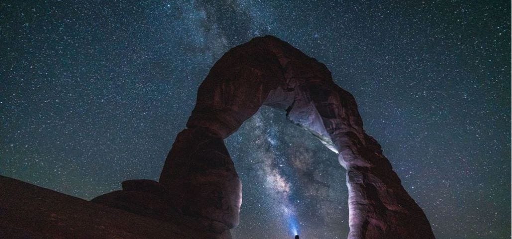 A girl is standing under the delicate arch