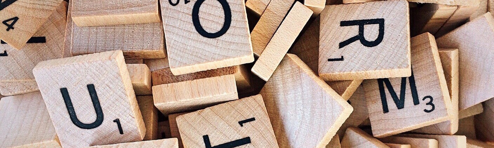 Close up view of Scrabble tiles, showing q, u, a, r, t, I, v, and m. Several tiles upside down.