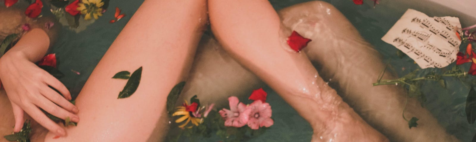 naked legs bathing in a bath with flowers