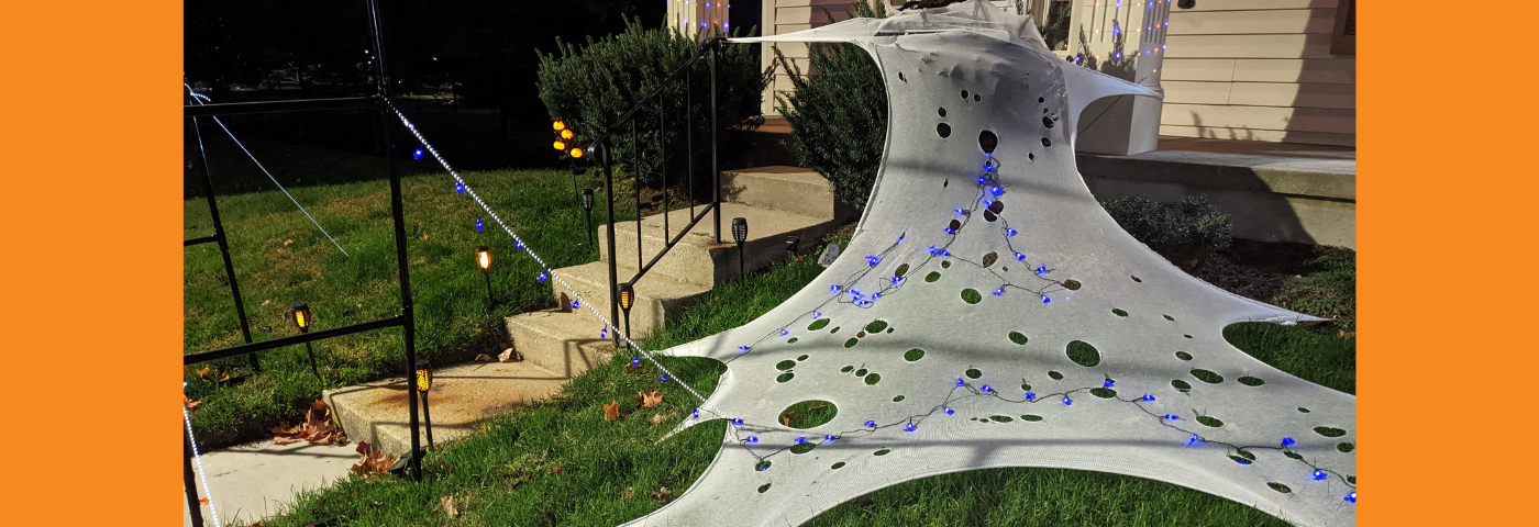 Yard at night with fake web and Halloween lights