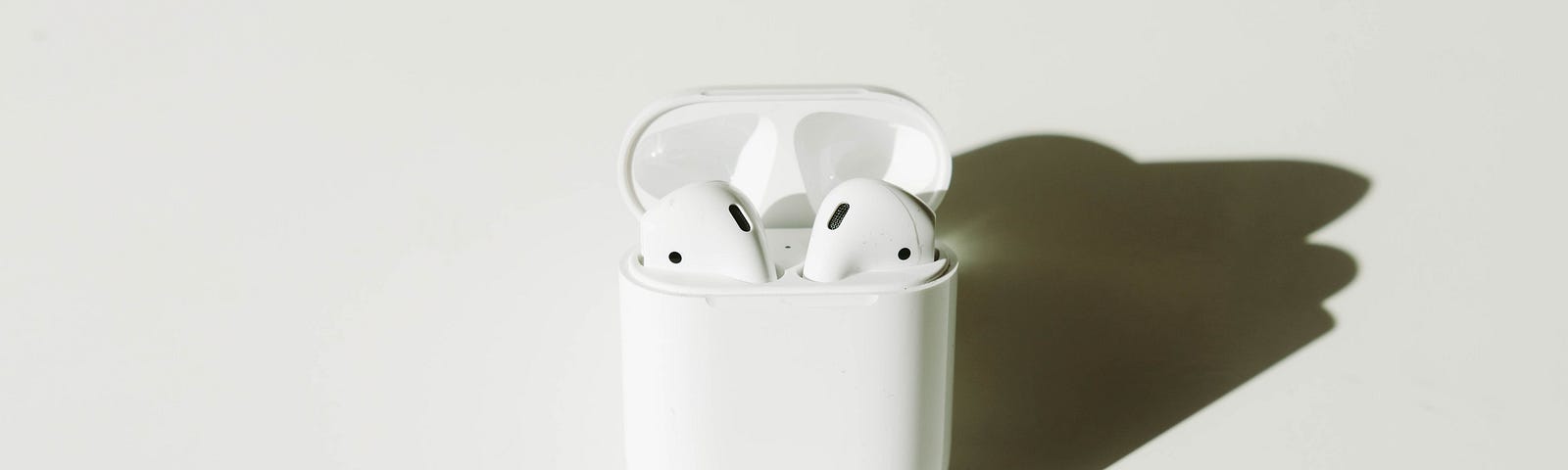 A pair of white headphone pods against a white background.