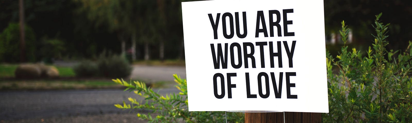 White sign with black words “you are worthy of love”