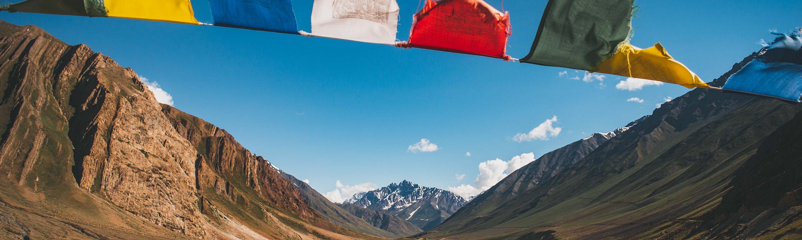 A string of colorful prayer flags with mountains in the background.