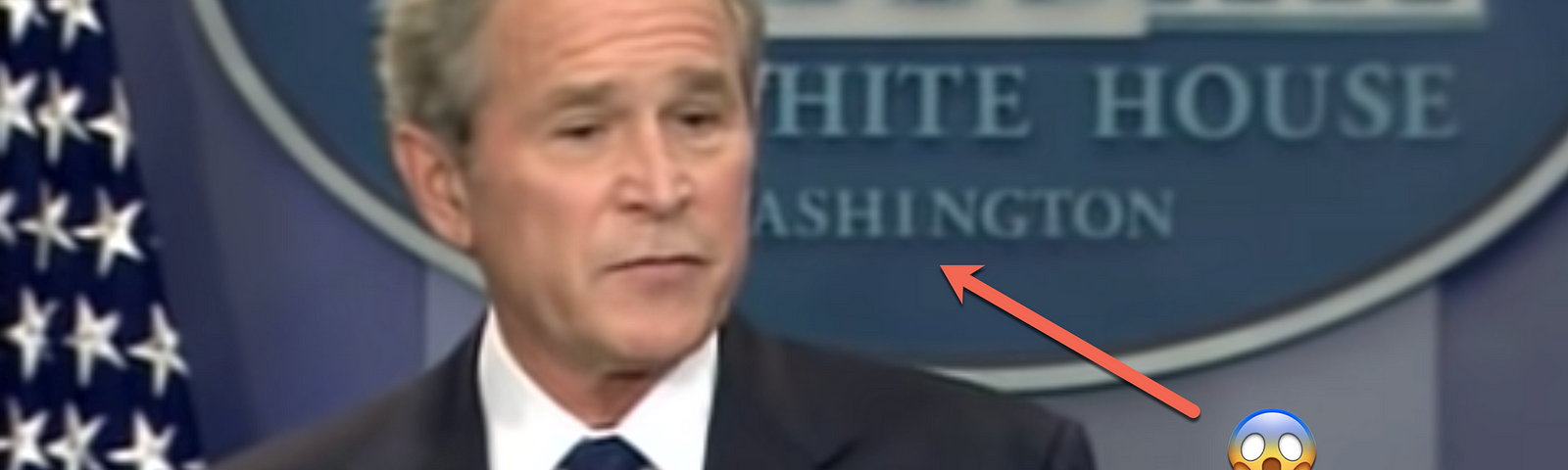 President Bush stands in front of the White House lectern. Behind him is a sign with a design error.