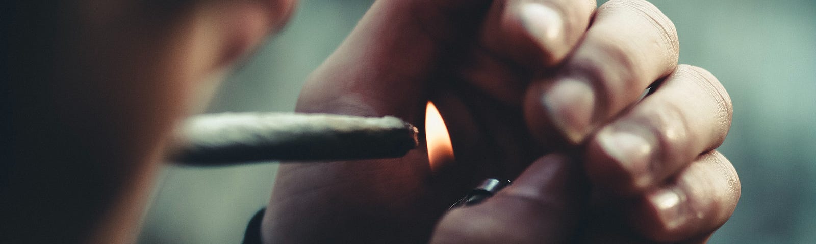 Young man lighting a marijuana joint
