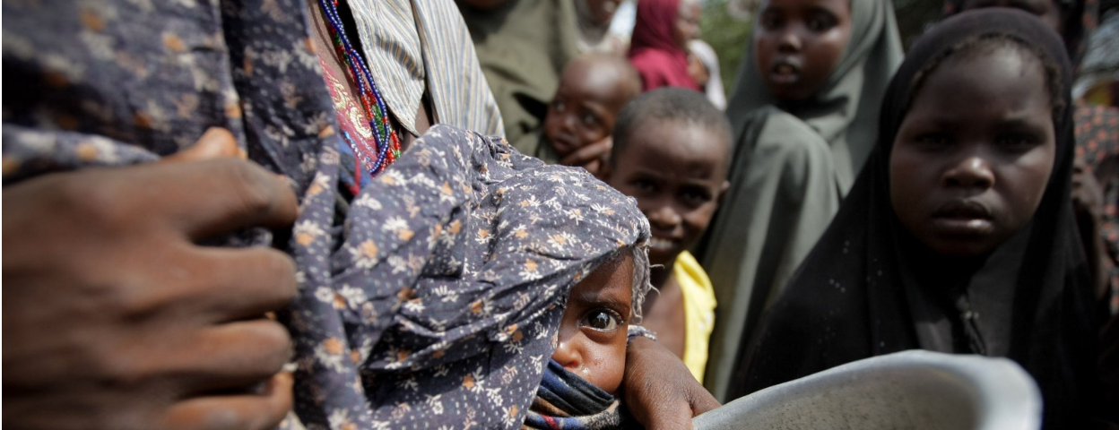 A woman holds her baby while waiting for food at the Badbado camp for Internally Displaced Persons (IDPs) during the 2011 famine in Somalia.