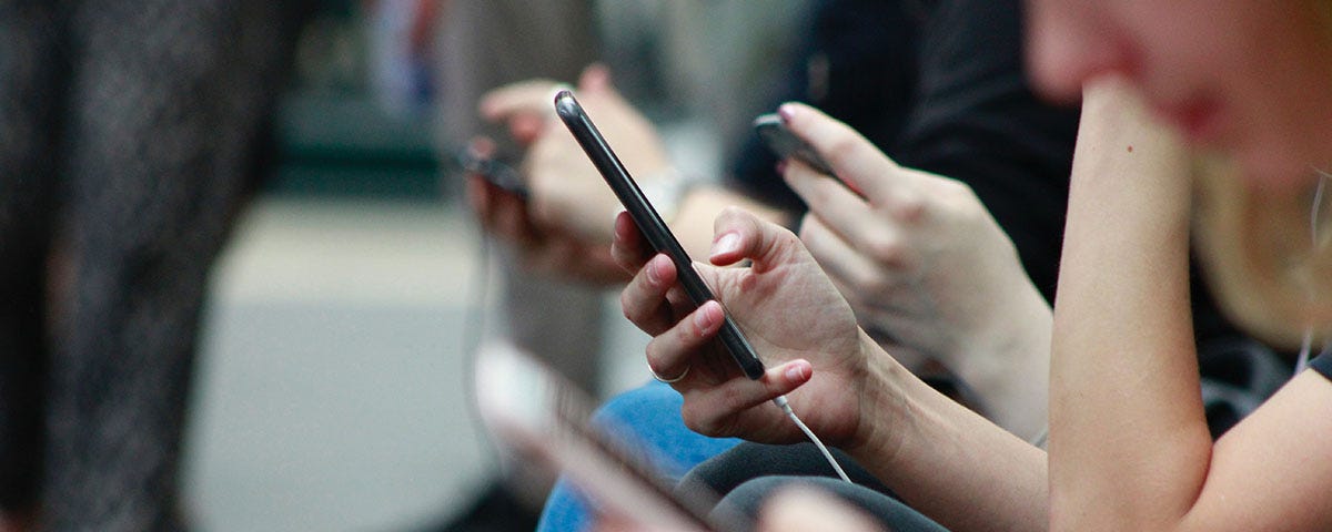 A row of people looking at their cellphones on a subway