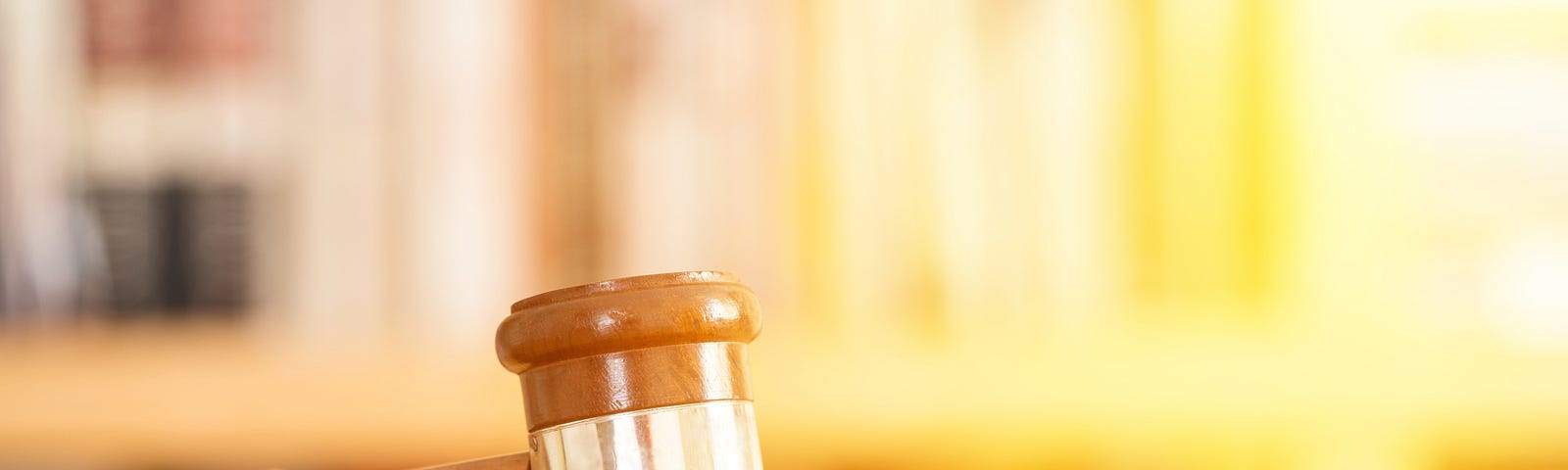 A photo of a wooden gavel in front of a bookshelf
