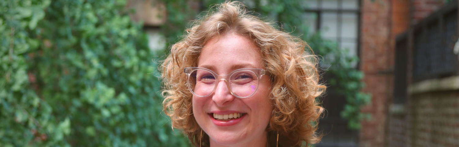 Headshot of Mel Friedel in front of a tree and a building.