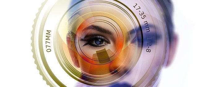 Woman’s face, slightly out of focus, with a camera lens superimposed