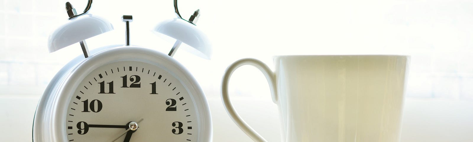 Alarm clock next to a coffee cup