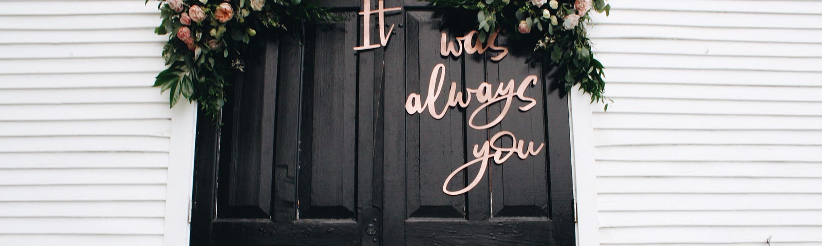 a door decorated with two bouquets and written on it the words, “it was always you”