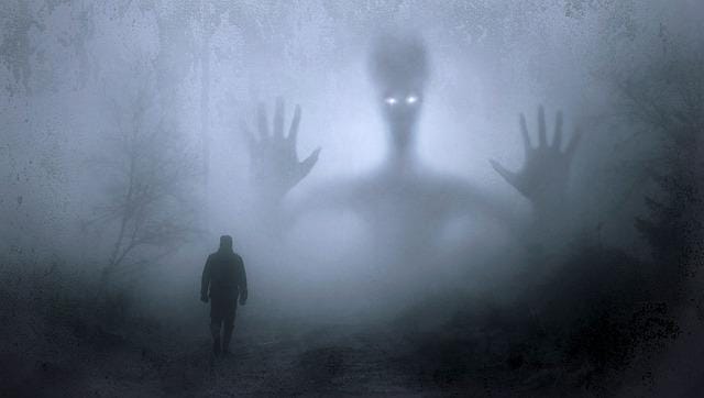 A huge spectral figure looms out of the mist in front of a lone male figure