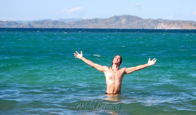 A man with victory pose in the sea.