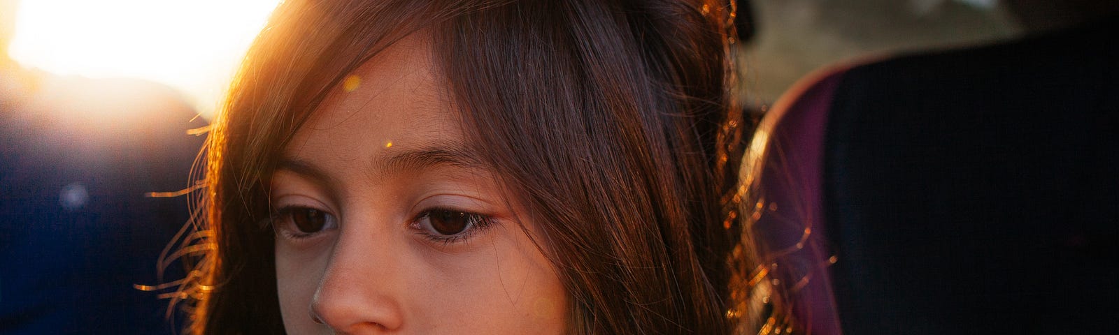 A close-up photograph of a young girl looking off into the distance.