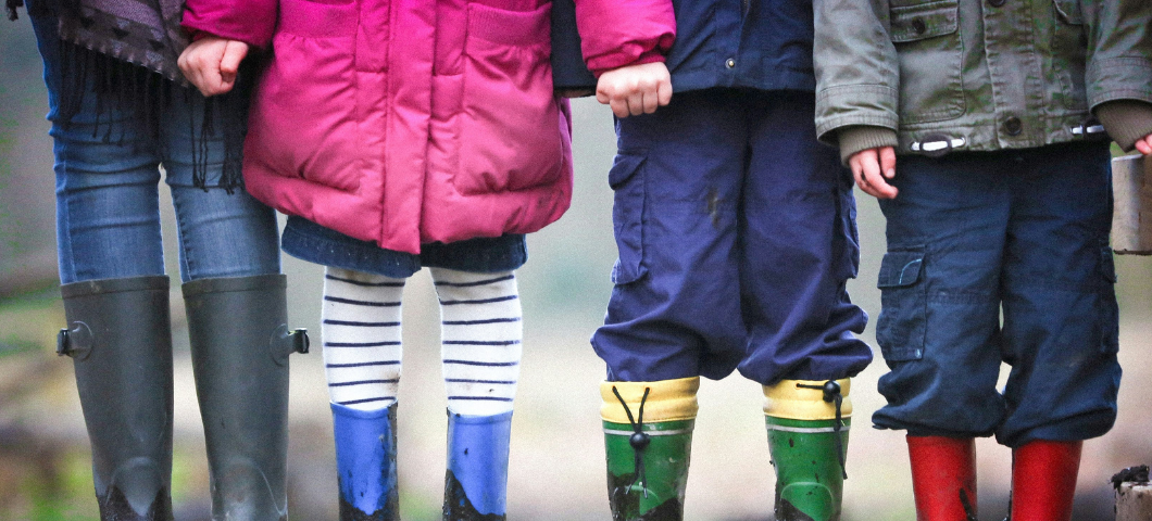 four children in boots and coats standing outside