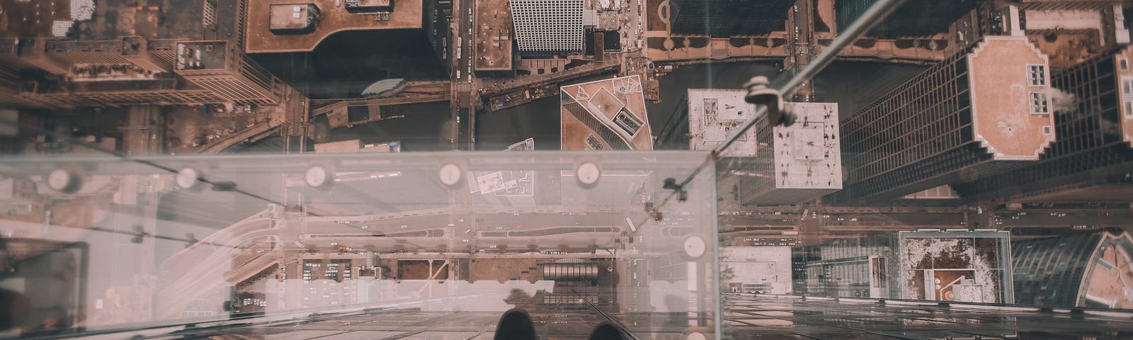 Someone standing on a glas ceiling looking down on their feet and the city beneath them from an ego perspective.