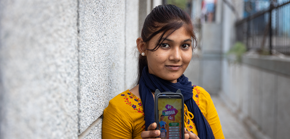 A girl holds a cell phone that displays a mobile game that teachers girls about menstruation.