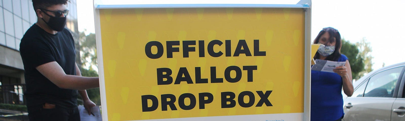 Pedestrians place ballots in a  mail-in ballot drop box outside of the L.A. County Registrar’s office.