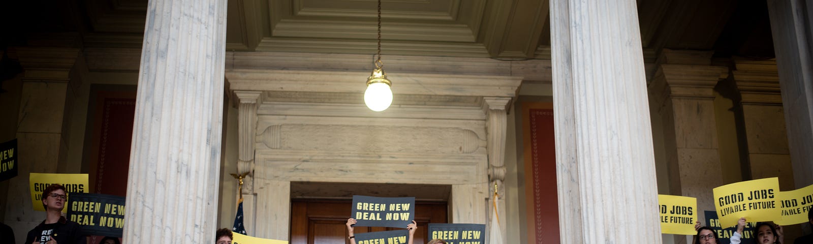 Young people with Sunrise holding “Green New Deal Now” and “Good Jobs Livable Future” signs.