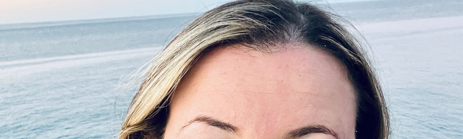picture of author smiling with the ocean in the background