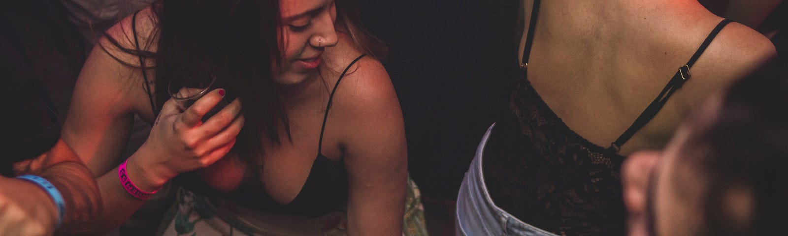 Two young girls dancing close together. They are wearing tank tops and look sweaty.