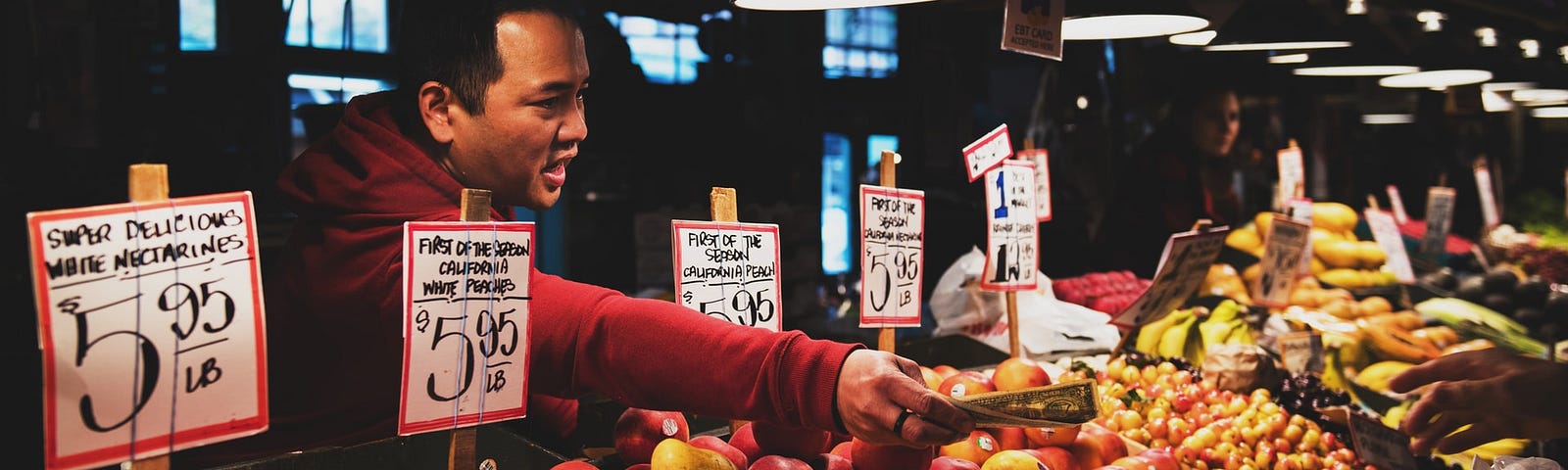 Man handing cash back to a customer at a produce stand