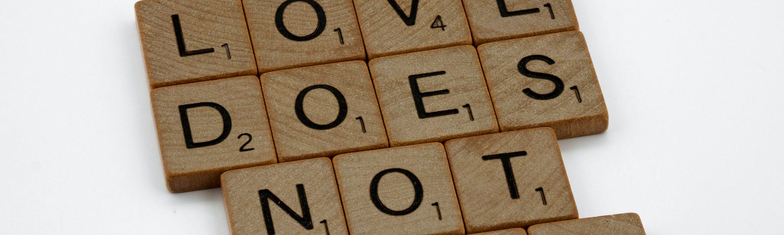 Scrabble tiles that spell the words on top of each other, “LOVE DOES NOT ENVY”