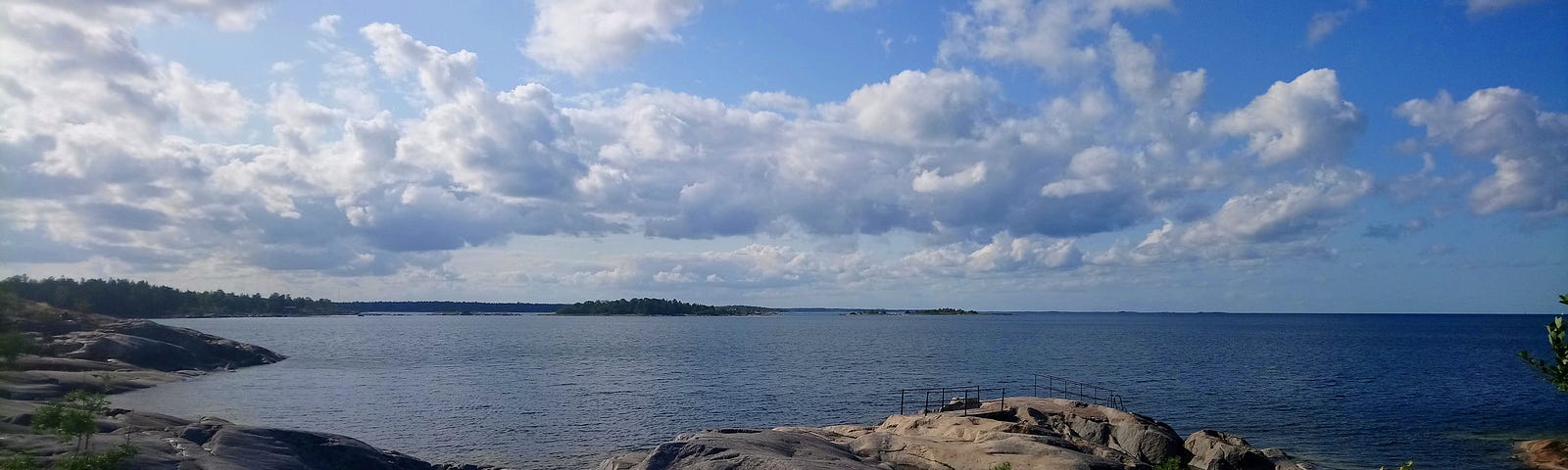 A rocky beach by a forest under a blue sky