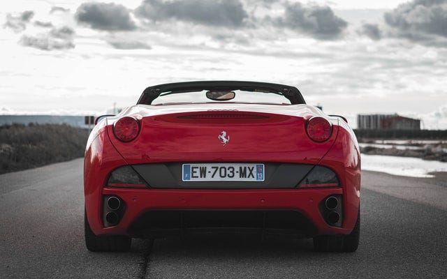 Rear view of a red Ferrari convertible on a highway.