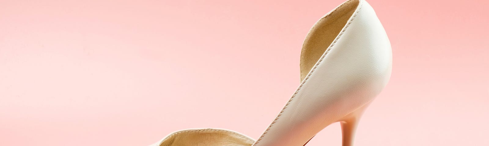 A white stiletto heel steps on an egg, breaking it