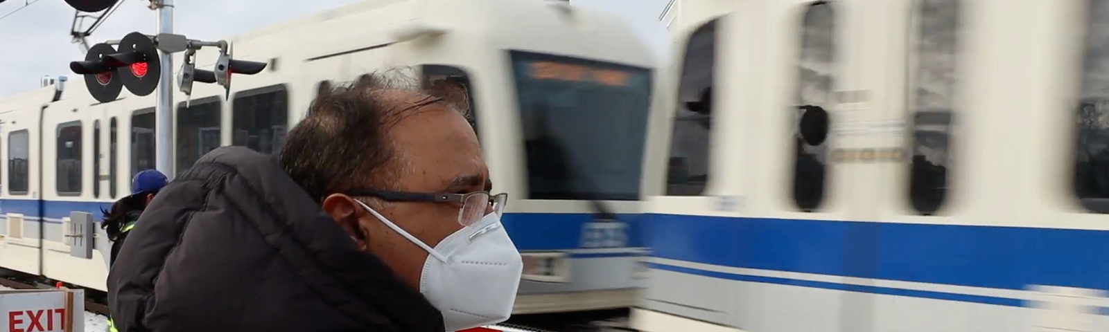 The Mayor waits to cross the tracks at and LRT station as the train goes past.