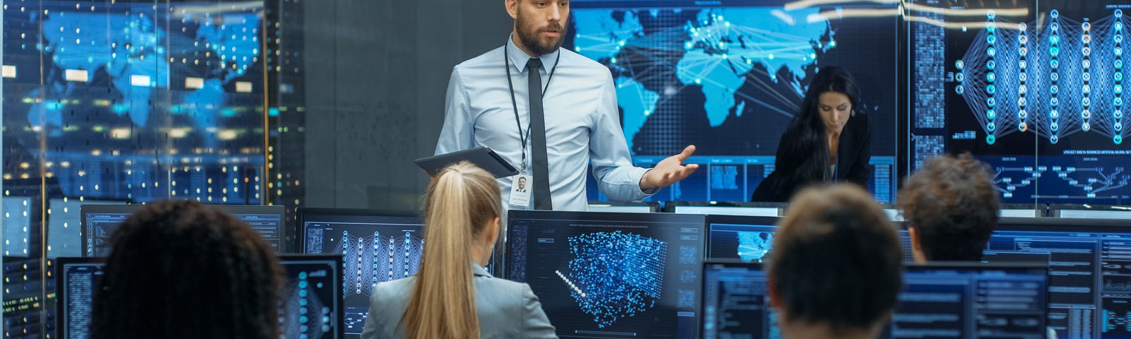 Lecturer and cyber security students sit in front of computer screens during class, practicing on a cyber range platform