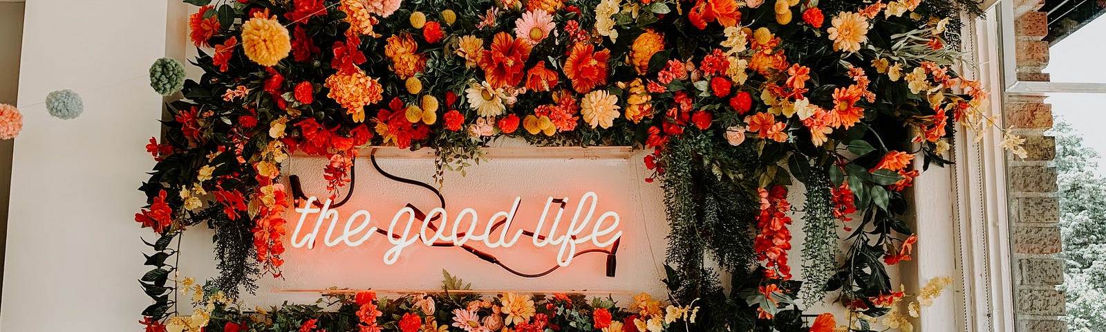 A sign surrounded by flowers at Goldenrod reads “The Good Life”