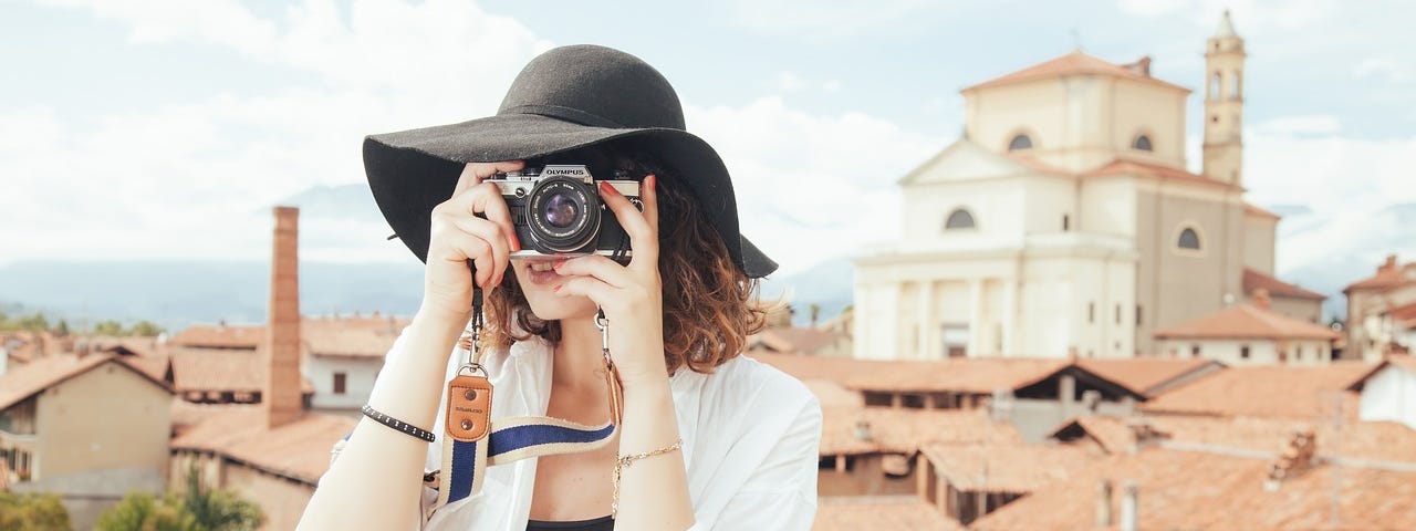 A woman wearing a beautiful black hat taking a picture.