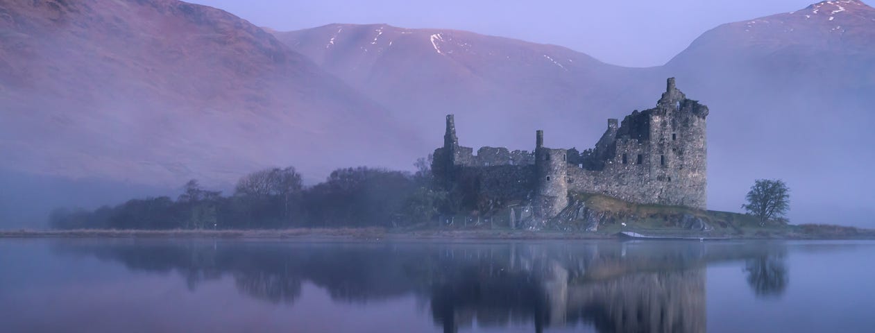 Misty photo of sunrise at Kilchurn castle in Scotland.