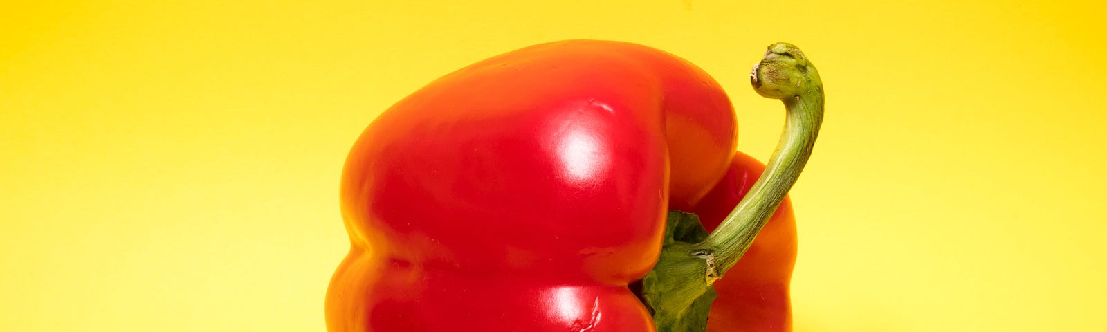 A red bell pepper on a yellow background