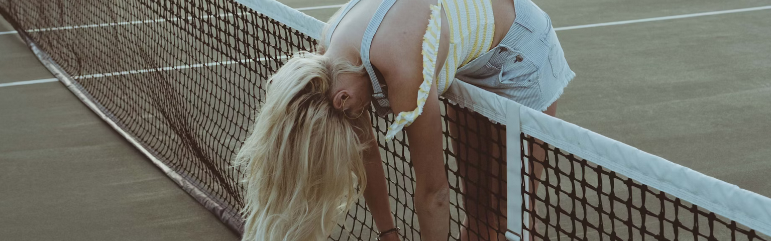 Woman bending over the net on a tennis court