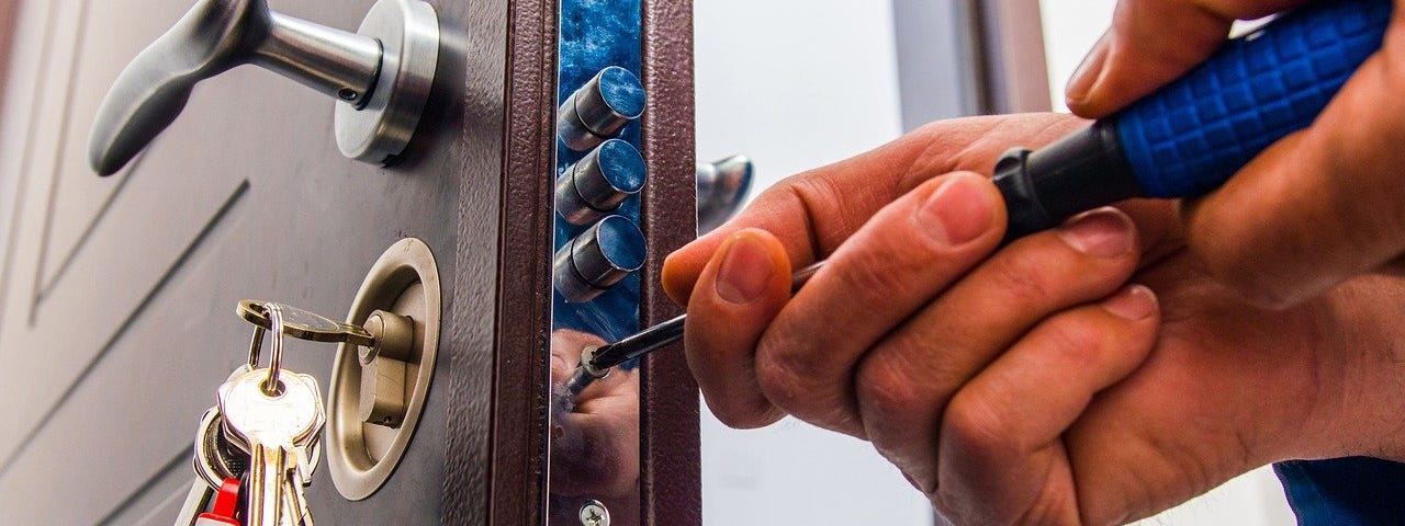 IMAGE: The hands of a locksmith working on a security lock with a screwdriver