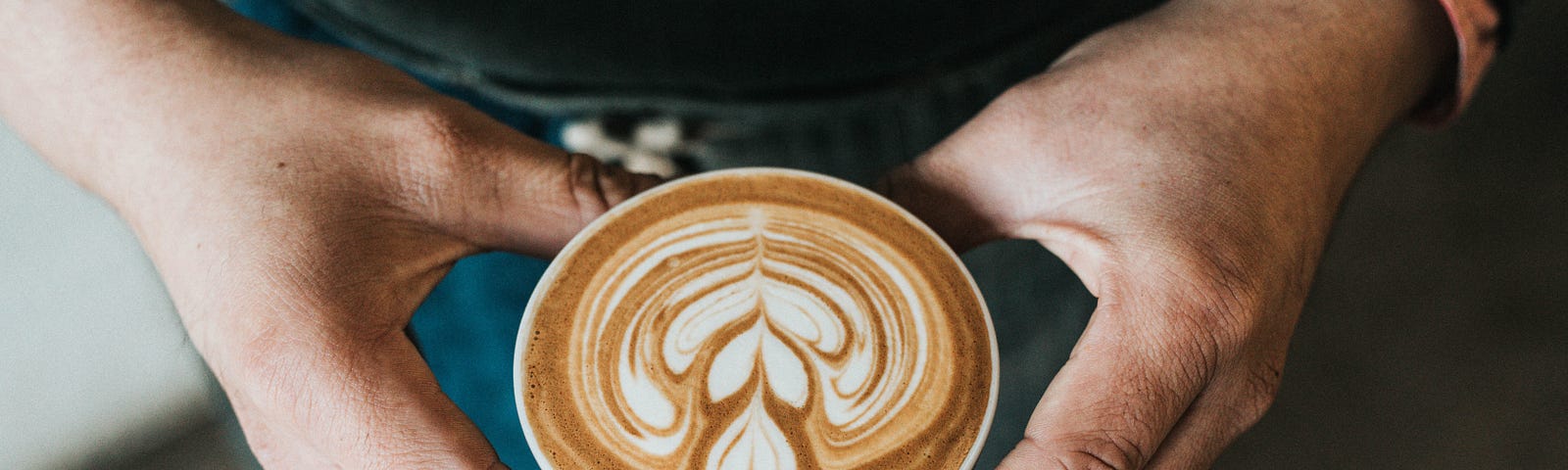 Close up of hands holding a cup of coffee with a heart