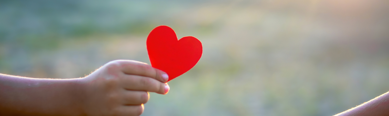 outreached hand holding a red paper heart, getting ready to place it in another person’s hand (on the right). Words in yellow script and sans serif — “Who gave you the best life-changing advice? Writing Prompt 39”