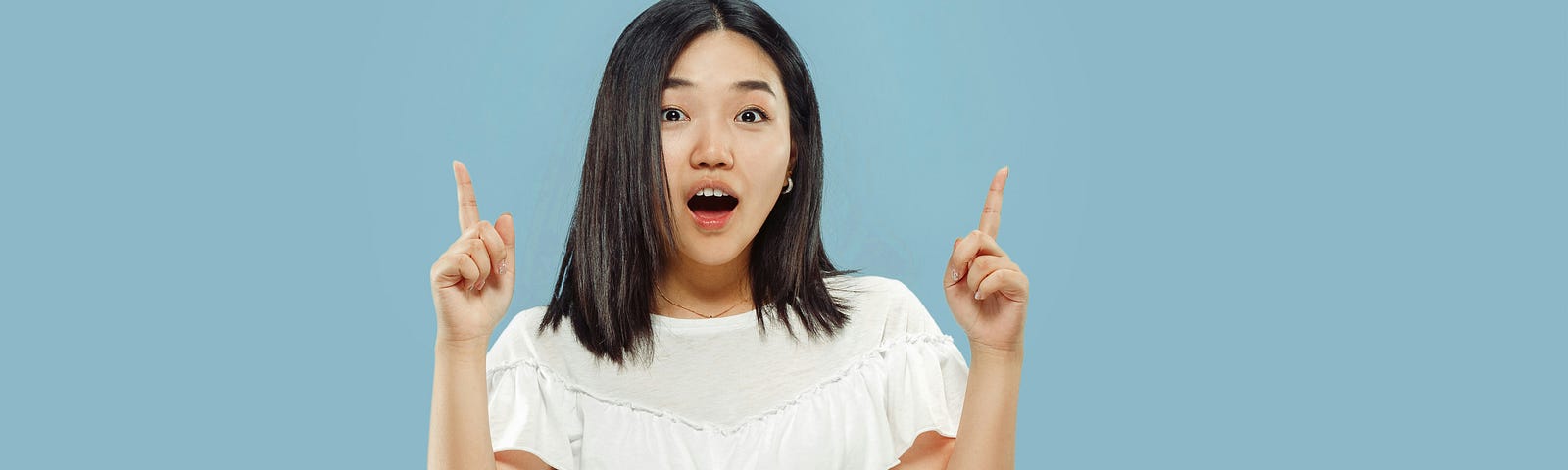 Asian girl with a surprised look on her face, wears a white shirt and black trousers. The background is blue.