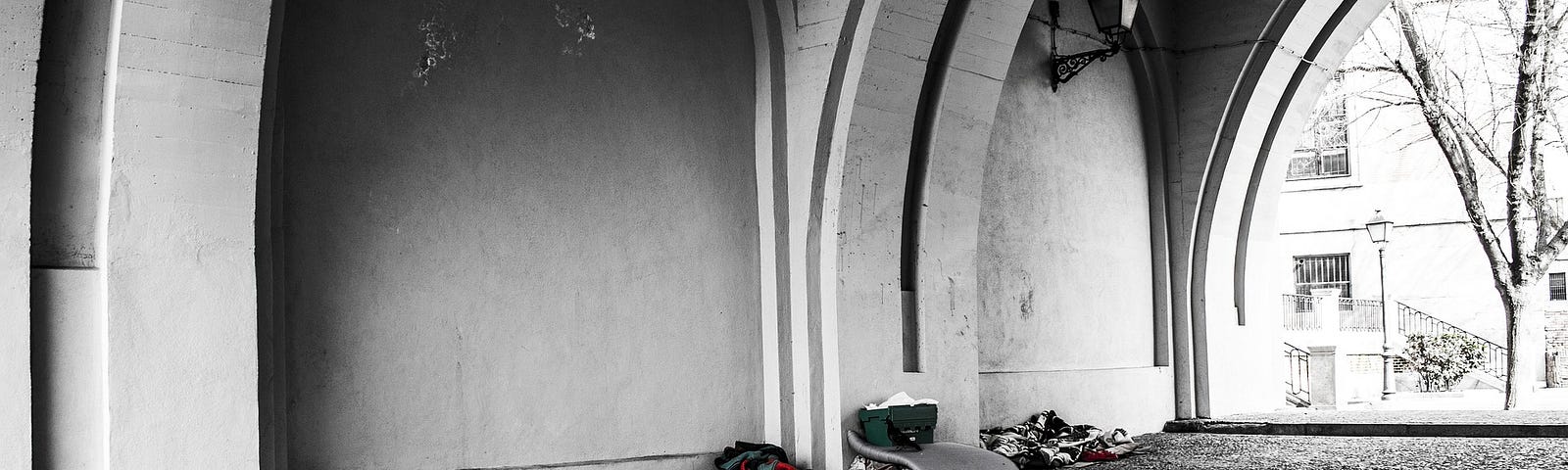 A few sets of blankets and belongings under a bridge